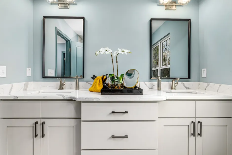 A serene modern bathroom featuring twin sinks, elegant faucets, and decorative mirrors.